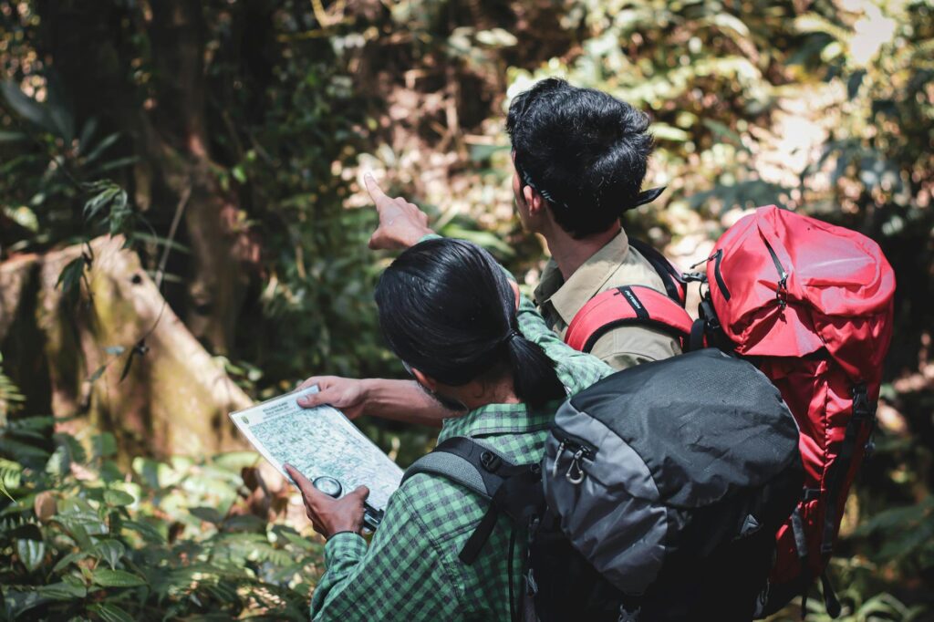 Hiker on a jungle trail in Sabah, Borneo, surrounded by lush rainforest near an orangutan sanctuary.