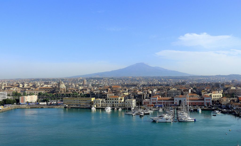 Catania's harbour and skyline with Mount Etna rising behind the city