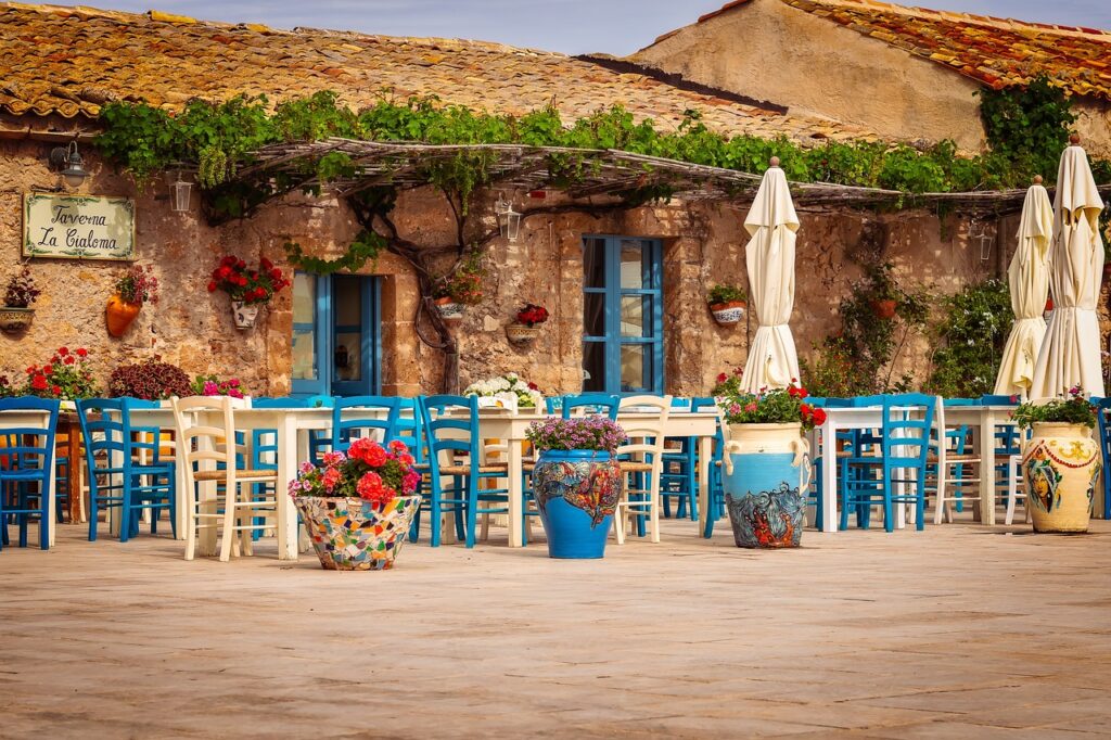 Blue and white chairs set out on the piazza at Taverna La Cialoma in Marzamemi