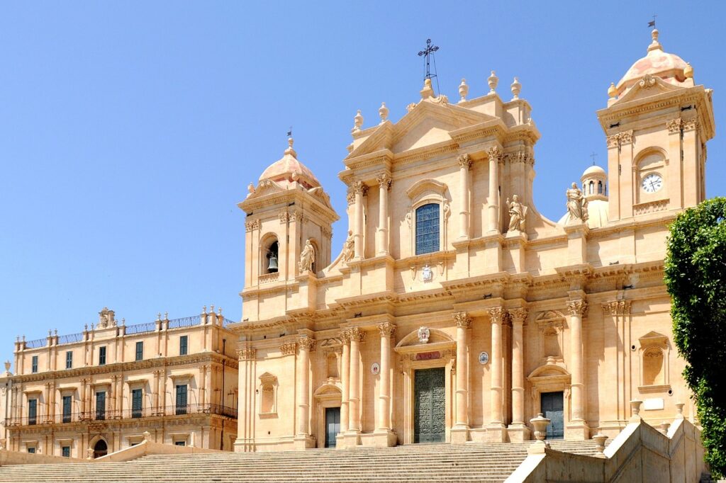 The honey-coloured baroque facade of Noto Cathedral above its wide stone steps