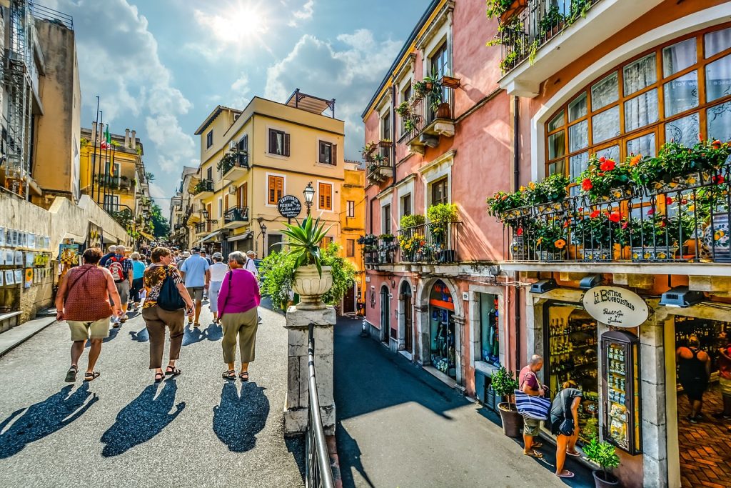 Shoppers on Corso Umberto in Taormina, lined with flower-filled balconies and shopfronts