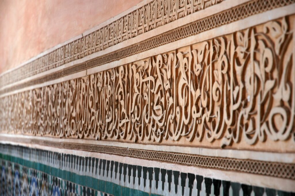 Carved stucco calligraphy and zellige tiles in the courtyard of the Ben Youssef Madrasa, Marrakech