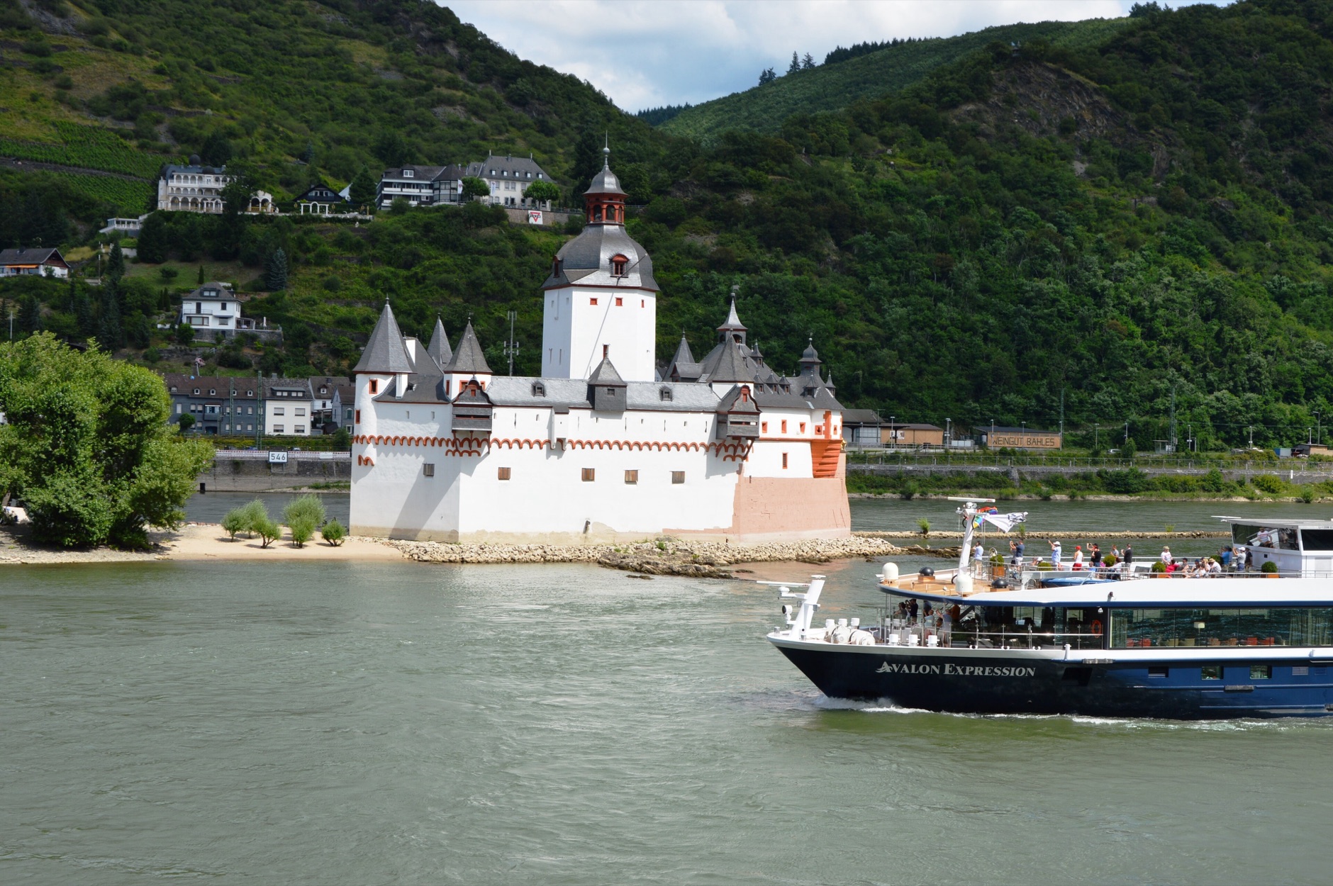 A river cruise ship passing Pfalzgrafenstein Castle on its island in the Rhine at Kaub, a highlight of any Rhine Valley travel guide
