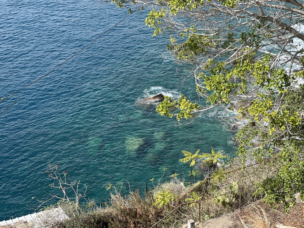 Clear turquoise water below the cliffs at Taormina