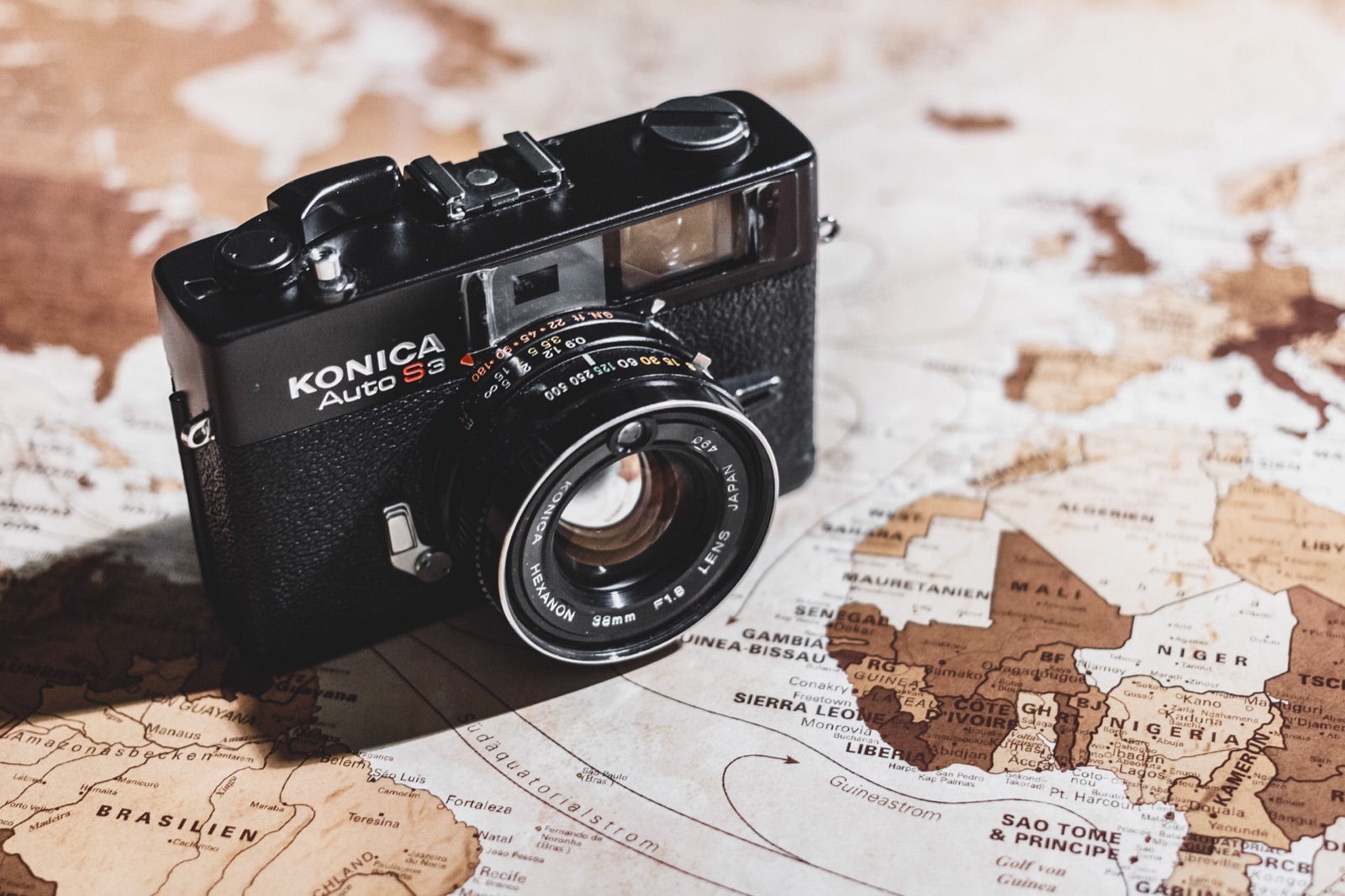 A vintage camera resting on a world map, symbolising the many places we've travelled and written about
