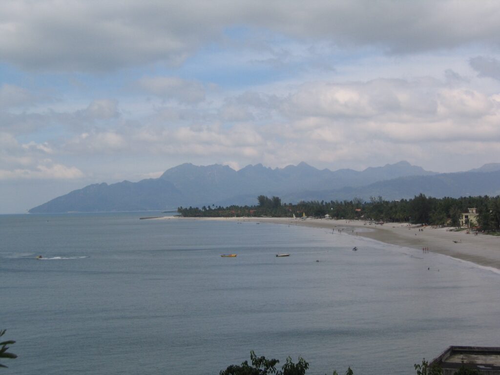 The long sandy sweep of Pantai Cenang, Langkawi, with the island's hills behind